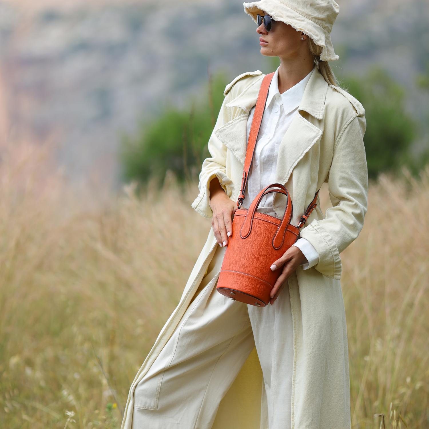 Alice bag in orange by Cecily Clune being carried in meadow
