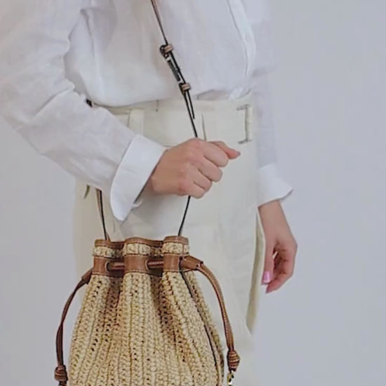 raffia and leather bucket bag worn on body