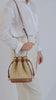 raffia and leather bucket bag worn on body